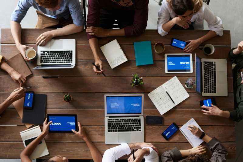 top-down photo of a team at a large table working on laptops